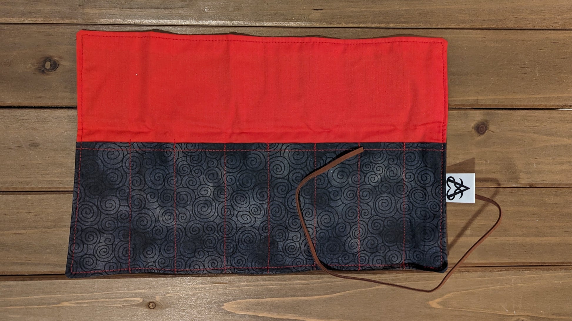 A short pen roll is open to show the bright red liner in the protective flap and 8 pocket channels with the same swirling fabric as outside.