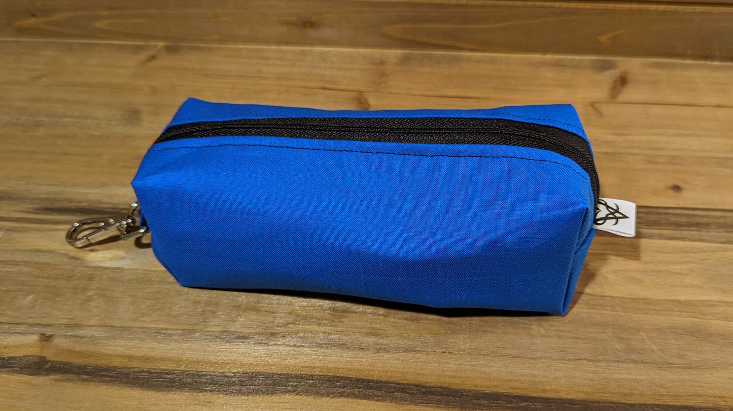 Another view of the blue Bag of Devouring to show the keychain clip at the top, black stitching along the zipper, and the Aras Sivad Studio logo on the bottom.