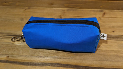 Another view of the blue Bag of Devouring to show the keychain clip at the top, black stitching along the zipper, and the Aras Sivad Studio logo on the bottom.