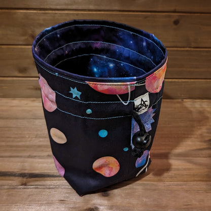 A drawstring bag with bright, colorful planets on the outside and a matching galaxy print liner.