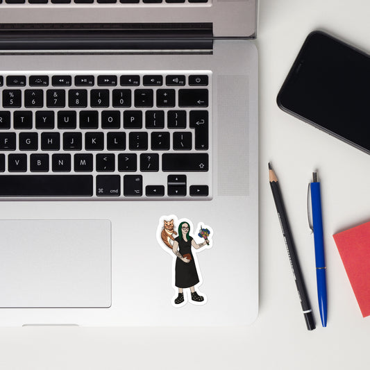 A laptop sticker has an illustration of Aras with green hair and a black dress holding a brown box and flowers. A ghostly Rufus touches her shoulder.
