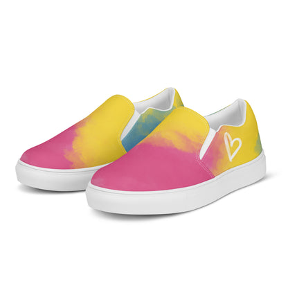 A pair of slip on shoes with color block pink, yellow, and blue clouds, a white hand drawn heart, and the Aras Sivad logo on the back.