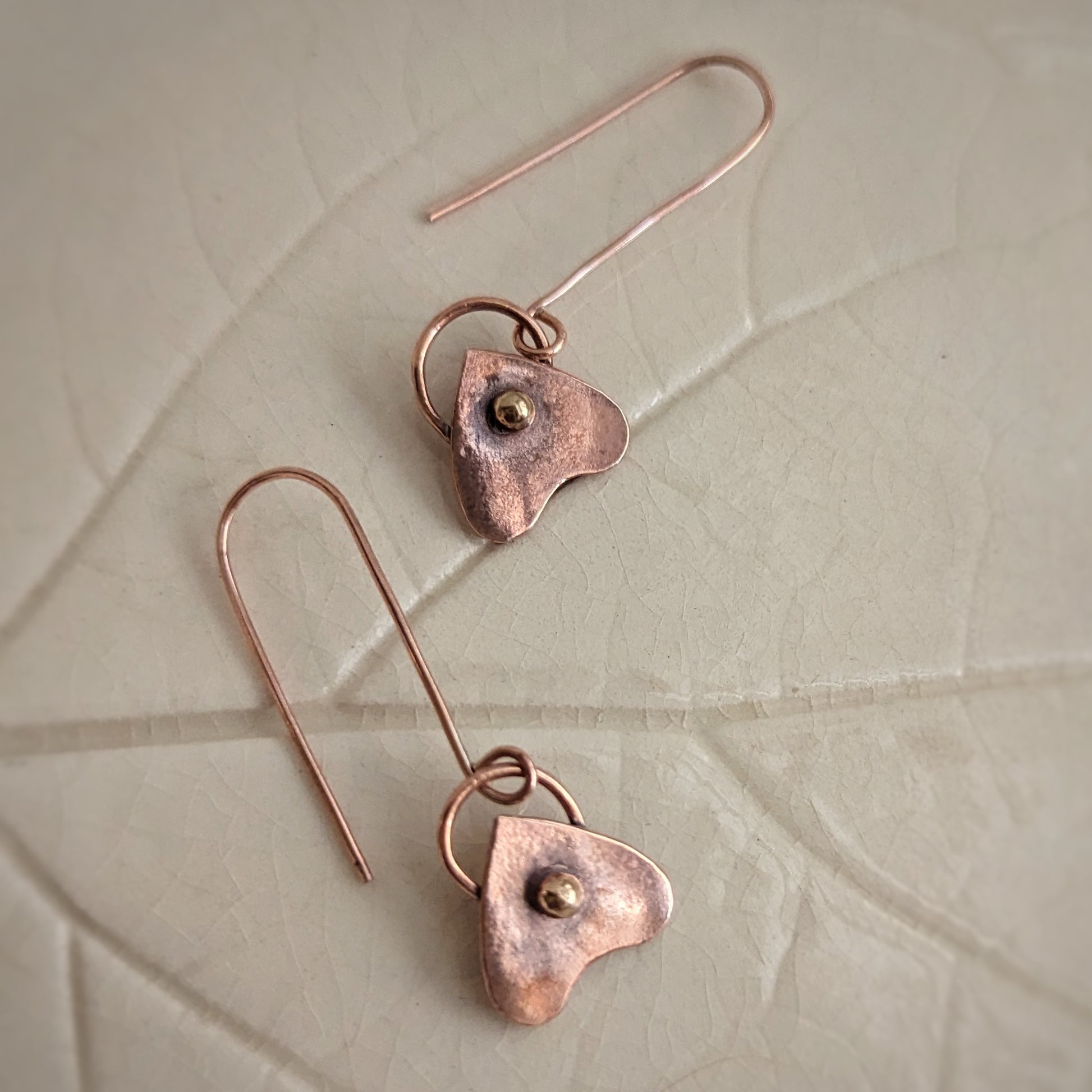Tiny copper planchettes have a gold brass round pip in the viewing area and a swirling bail back on long copper hooks.