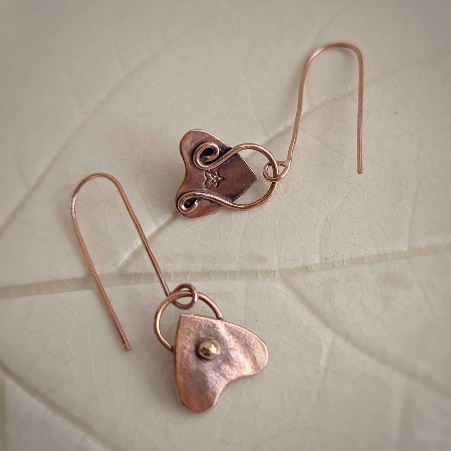 Tiny copper planchettes have a gold brass round pip in the viewing area and a swirling bail back on long copper hooks.
