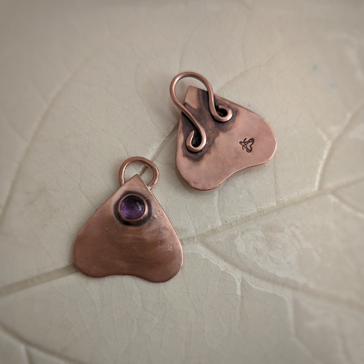 Two planchette pendants, one with amethyst set in the front, and the other turned to show the decorative bail and the Aras Sivad Studio stamp on the back.