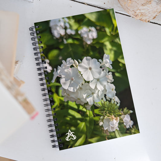 A spiral notebook is covered with a picture of a white garden phlox flower cluster on a sunlit bush with the Aras Sivad Studio logo in the bottom corner.