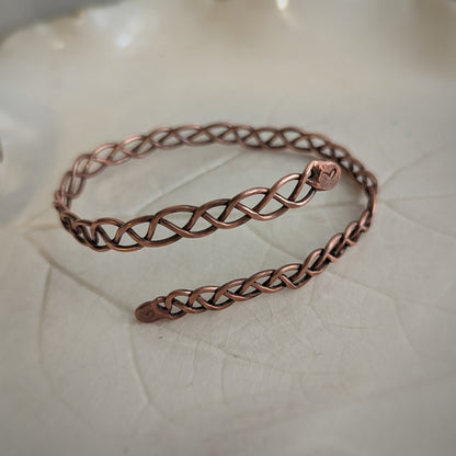 A copper braid bangle has fused ends which have been filed down, stamped with a heart, and given a patina for definition.