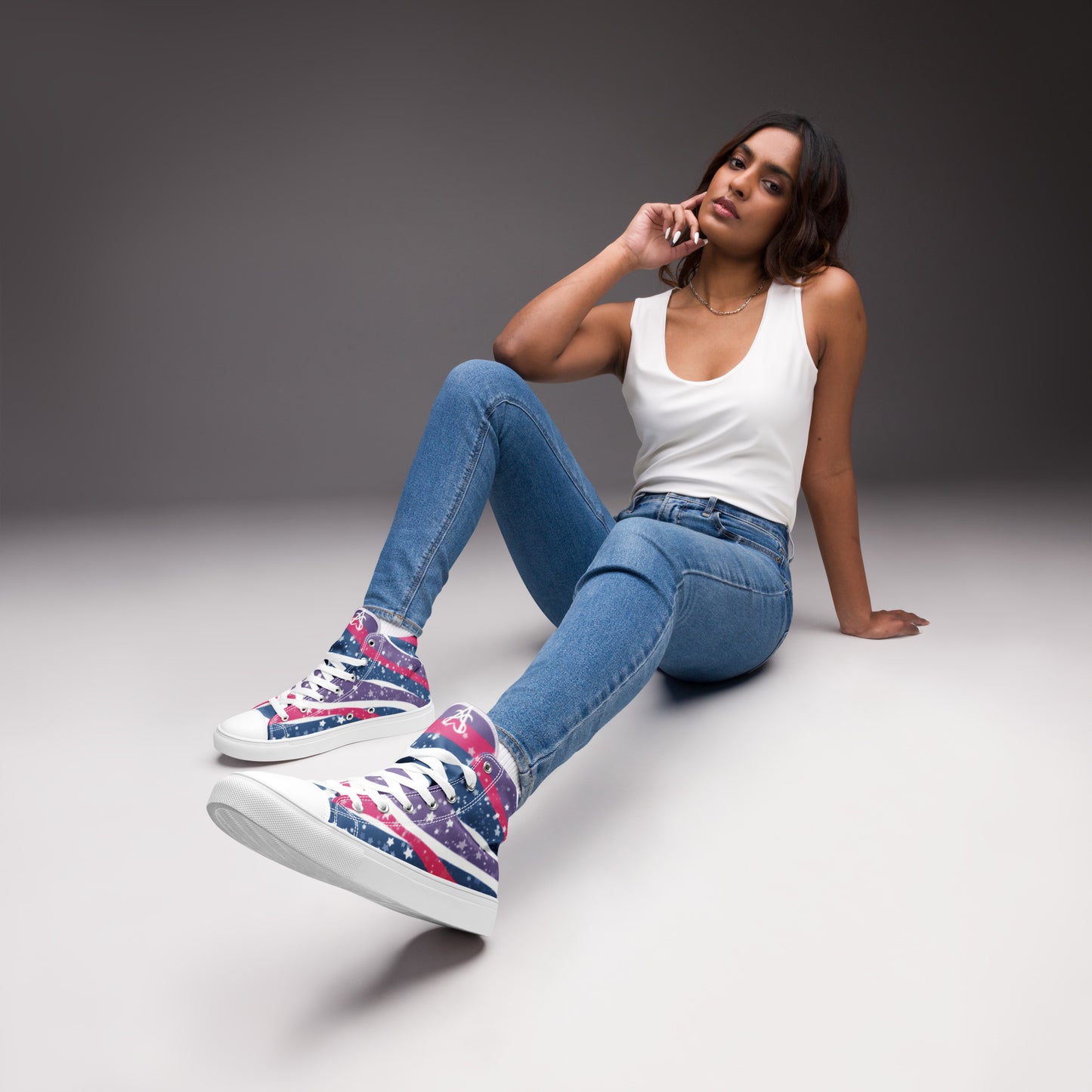 A model wears a pair of high top shoes with pink, purple, and blue ribbons that get larger from heel to laces, white stars, and the Aras Sivad logo on the tongue.