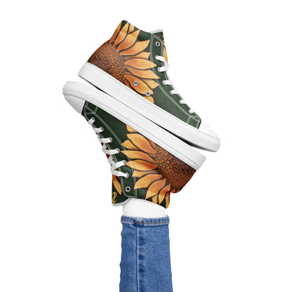 A model wears a dark green high top shoe with a large sunflower painting on the side, the middle starting around the heel and the petals wrapping around the side of the shoe, almost to the laces. Its pair balances on top.