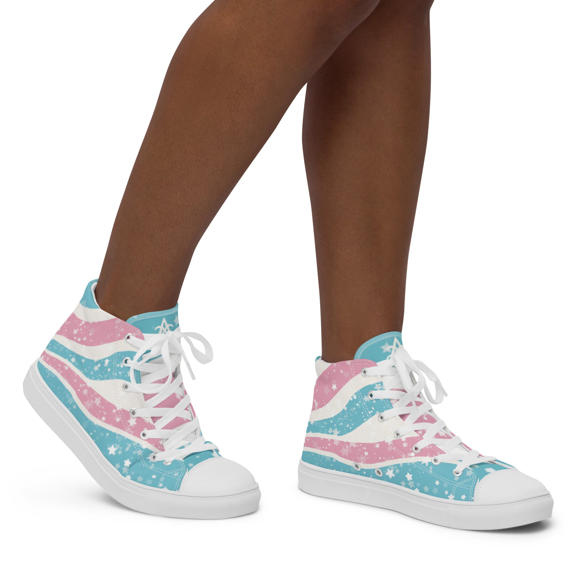 A model wears a pair of high top shoes which have way lines starting from the heel and getting larger towards the laces in pink, white, and blue with white stars all over, white laces, and white details.