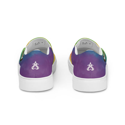 Back view: A pair of slip on shoes with rainbow clouds wrapping around the shoe, a double heart in black and brown with the trans pride flag inside, and the Aras Sivad Studio logo on the back of the heel.