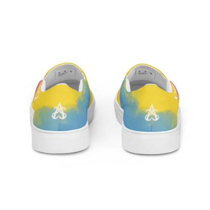 Back view: a pair of slip on shoes with color block pink, yellow, and blue clouds, a white hand drawn heart, and the Aras Sivad logo on the back.