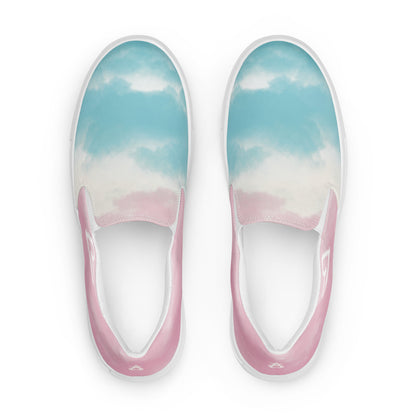 A pair of slip on shoes has a cloud pattern with color blocked areas of blue, white, and pink, a white doodled heart on the outside, and the Aras Sivad Studio logo on the heel.