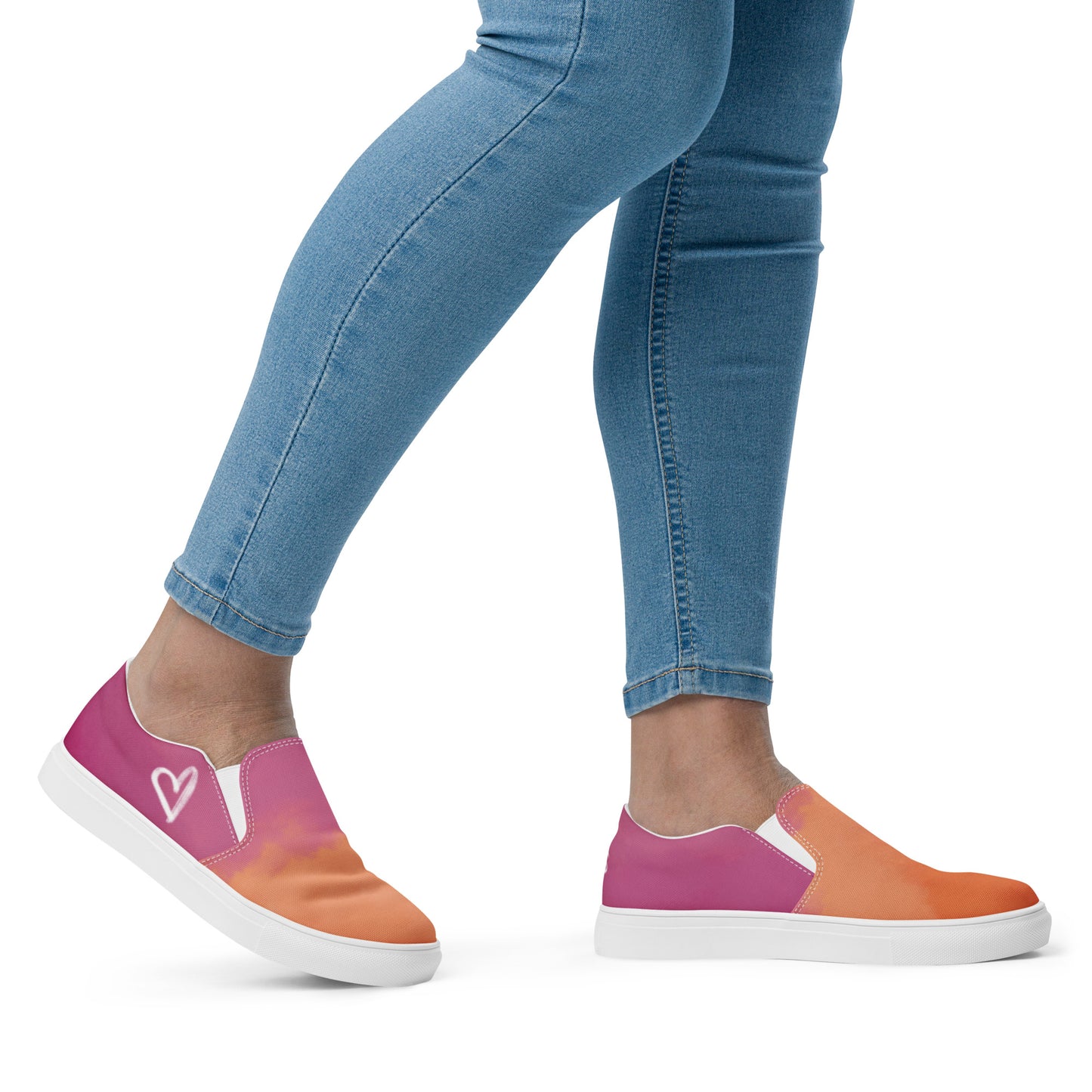 Right view: A model wears a pair of slip on canvas shoes with the colors of the lesbian pride flag in a cloudy texture, a white heart on the side, and the Aras Sivad logo on the back.