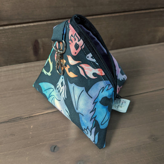 A D4 shaped bag with rainbow dragons sits on a wood surface.