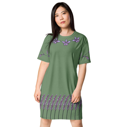 A model wears a sage green t-shirt dress with lavender watercolor floral patterns: lavender flowers around the bottom, a vine with leaves and flowers on the sleeves, and three flowers ringing the neckline.