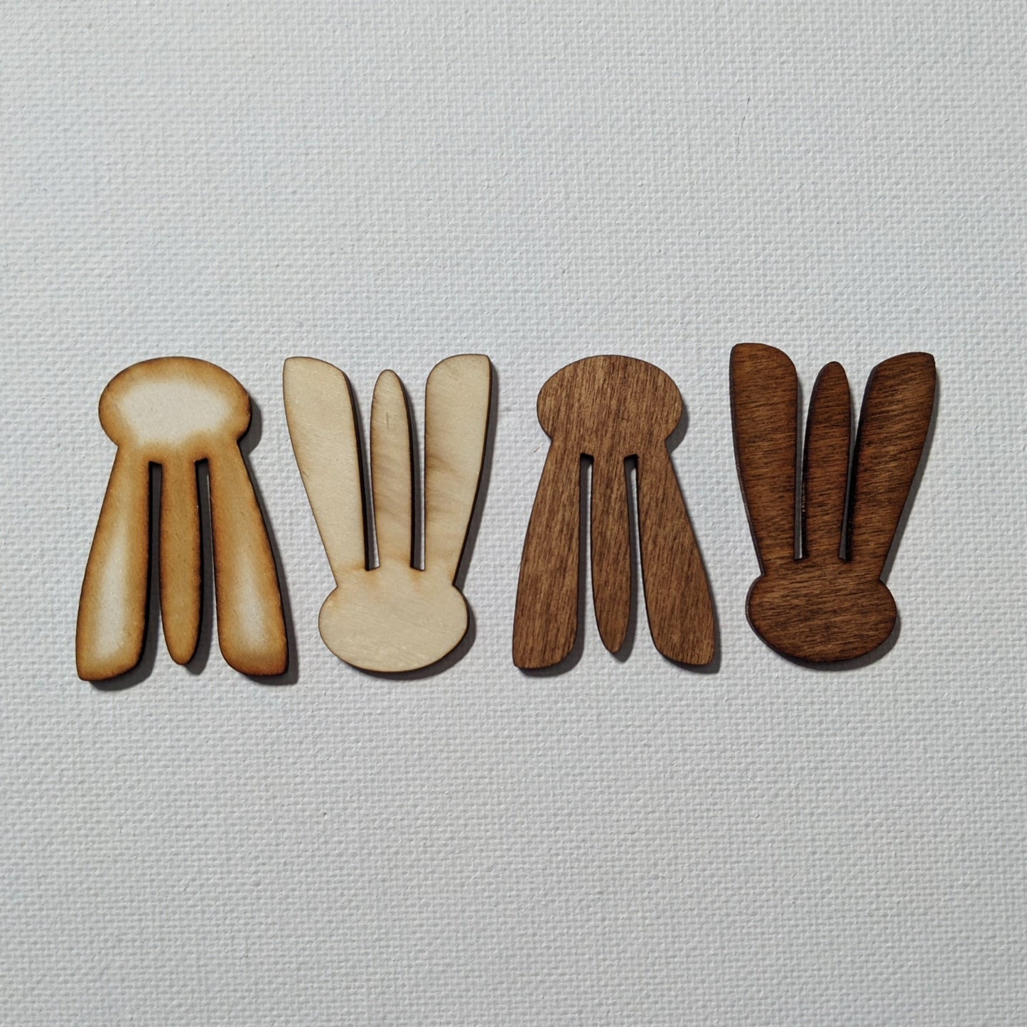 Four 3-pronged wood clips sit on a white textured surface.