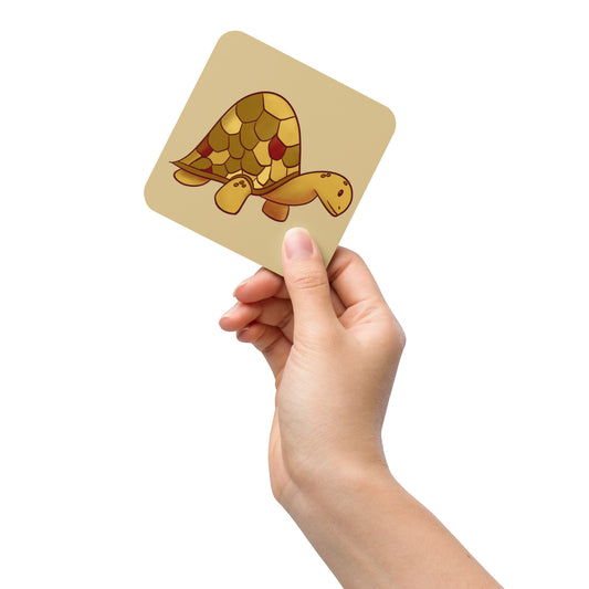 A hand holds up the Golden Turtle coaster for scale.