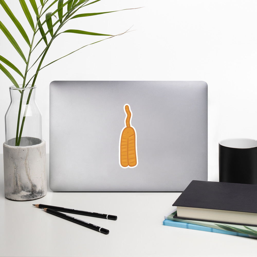 A sticker of an orange cat butt doodle is on a laptop surrounded by office supplies.