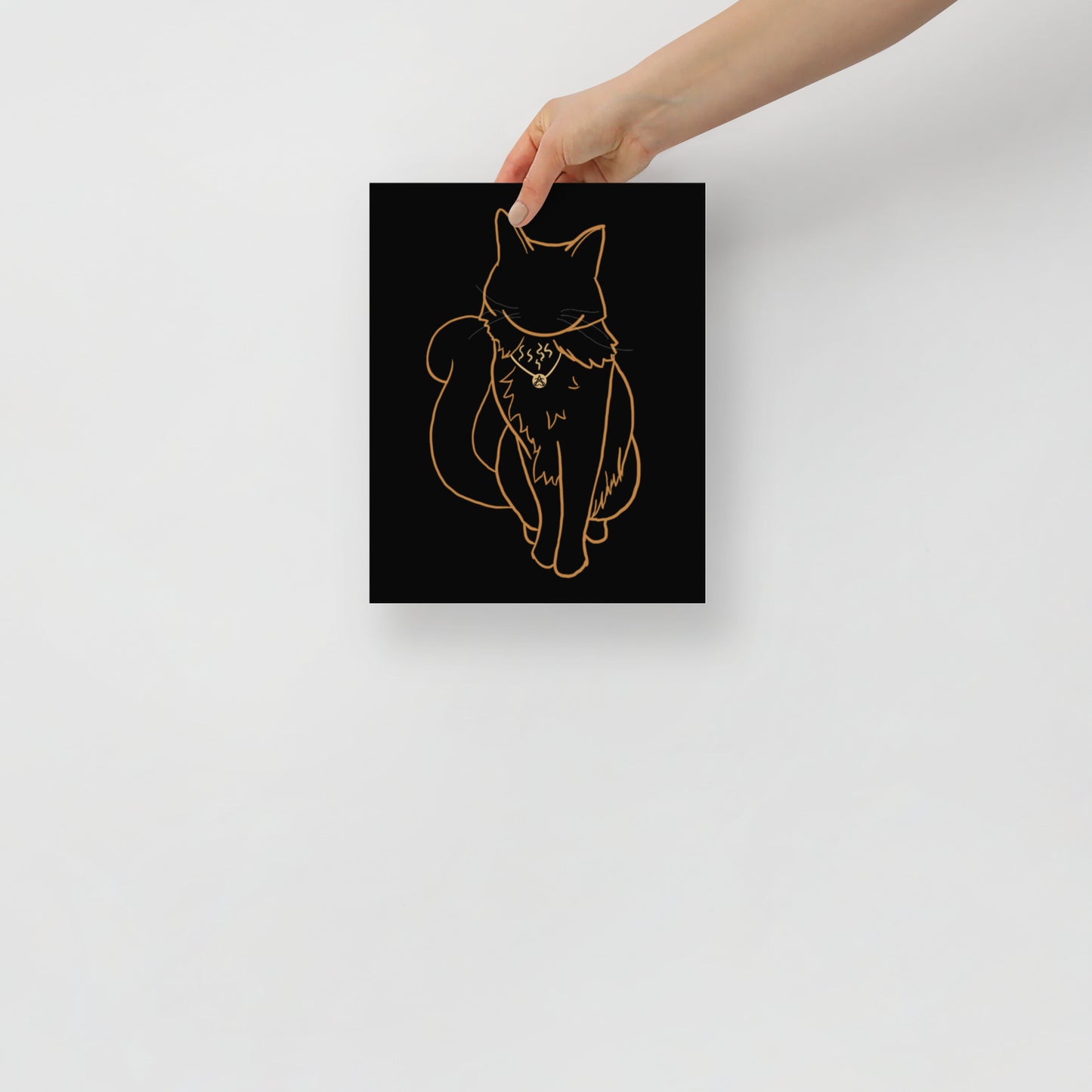 A hand holds a 8" by 10" poster with the line art drawing of Rufus the cat by Aras Sivad.