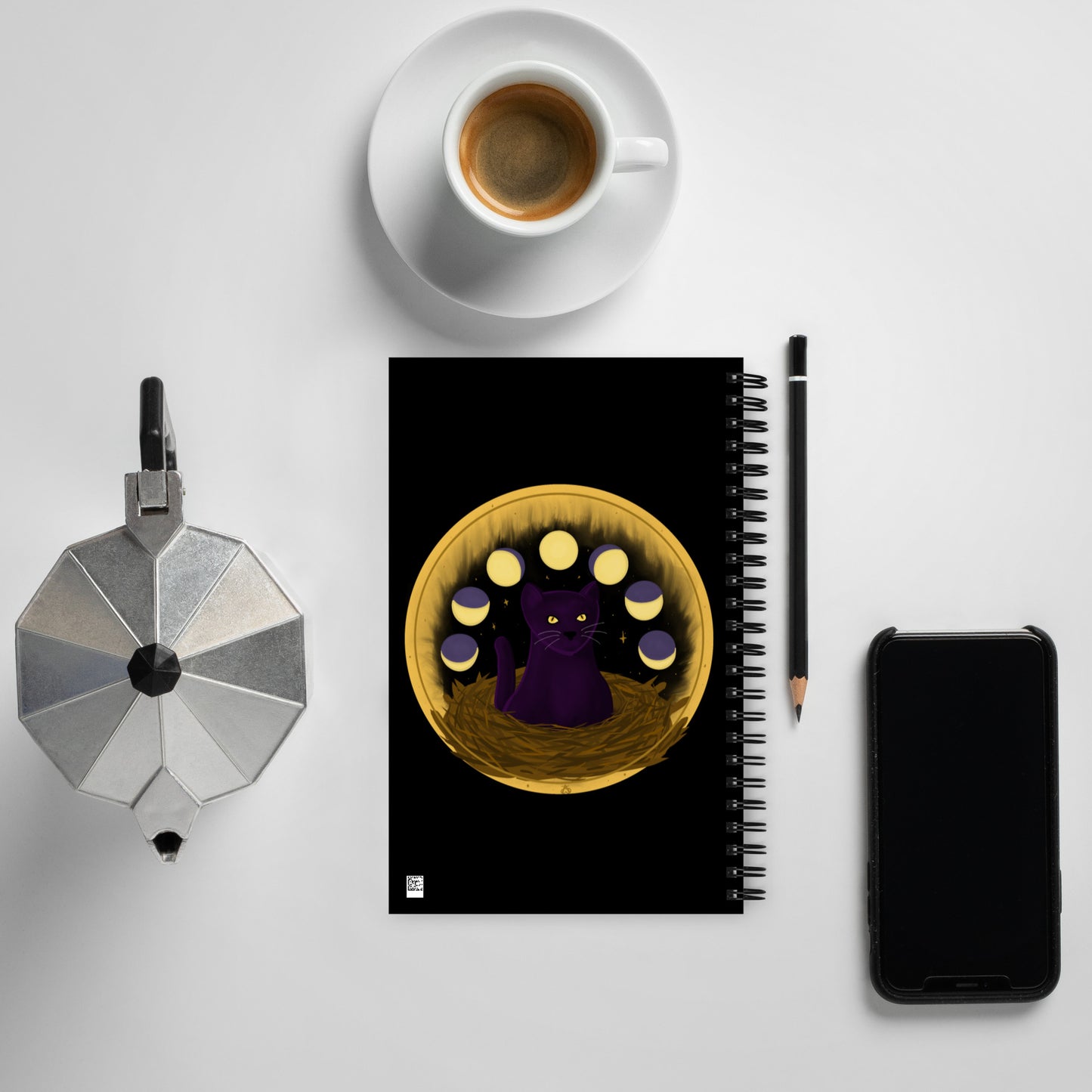 Back view: A black notebook with a painting of a dark purple cat with golden eyes sitting in a nest, ringed by the phases of the moon and golden stars behind it.