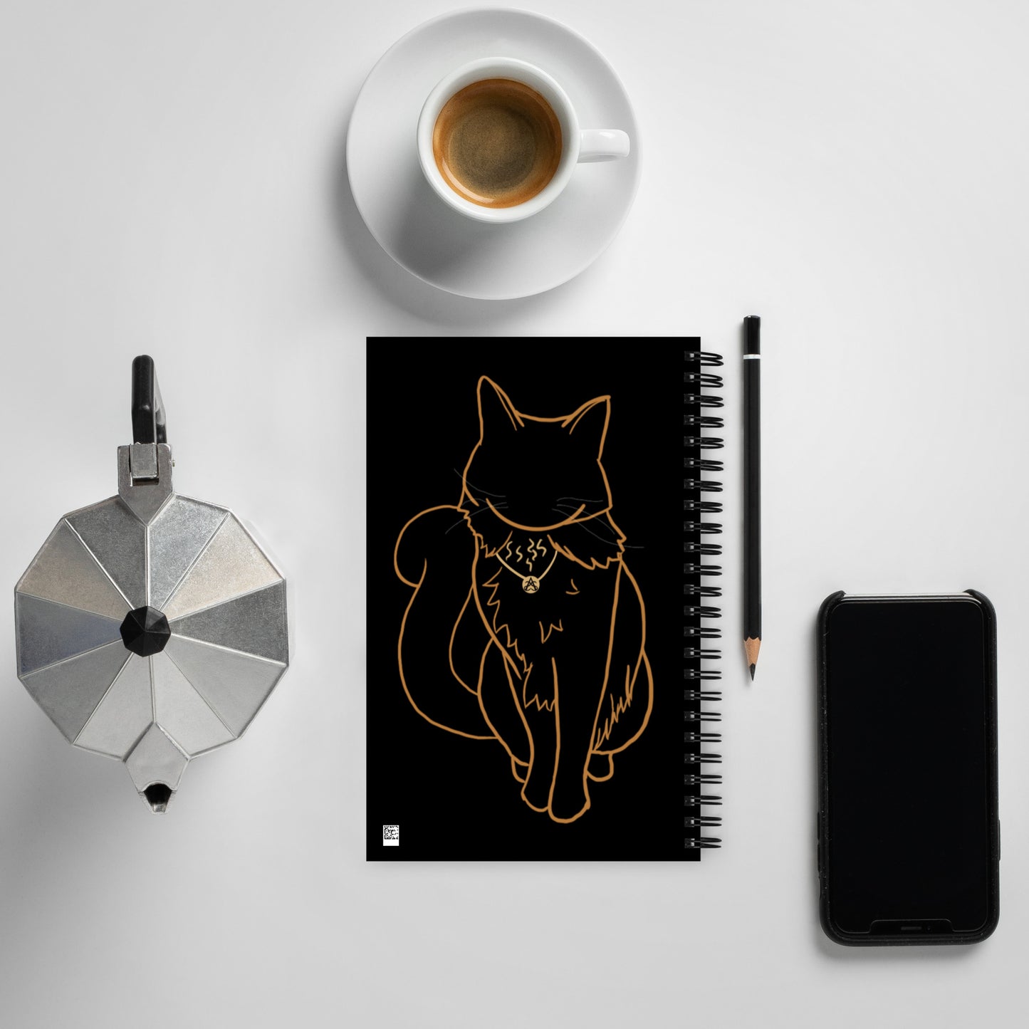 A black spiral notebook with the Rufus outline art by Aras Sivad is surrounded by a kettle, cup, pencil, and phone.